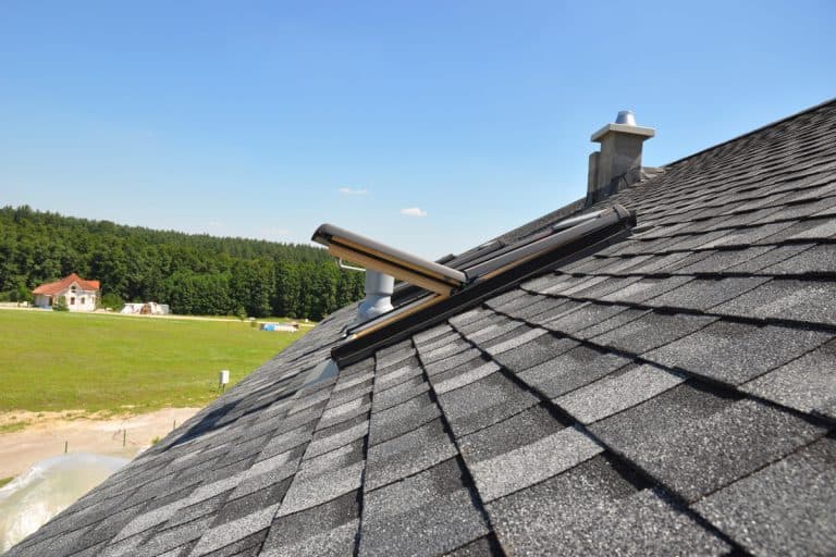 A roof covered with asphalt shingles and an opened rood window, Can You Put A Metal Roof Over Asphalt Shingles?