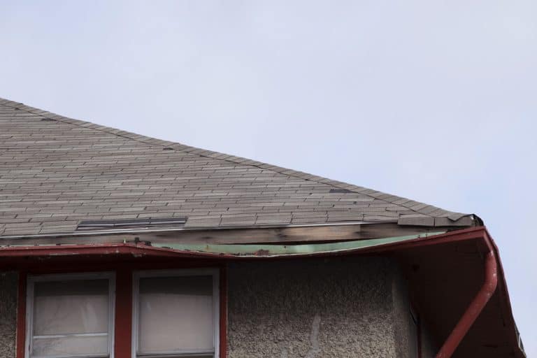A house with a bent gutter due to heavy rainfall and accumulating debris inside the gutter, Can You Repair A Bent Gutter? [Here's how to do that in 7 steps]