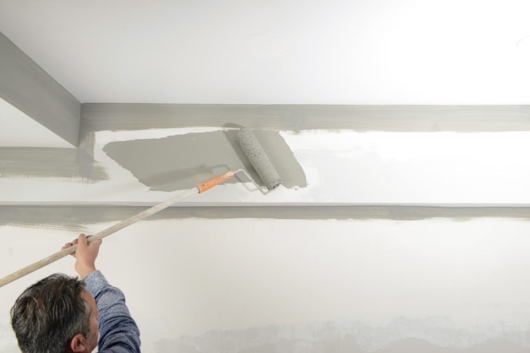 A painter painting the ceiling of a house with gray paint, Why is the Ceiling Bubbling when I Paint it? [4 Possible Causes and Solutions]