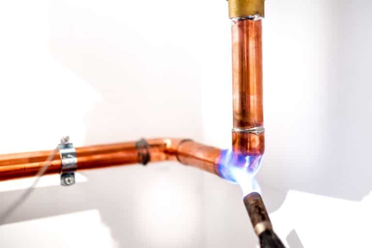 A plumber using a blow torch to secure a copper pipe in a water lne, How Long Do Copper Pipes Last And When To Replace Them?