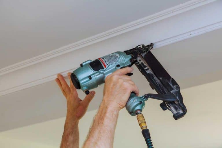 Carpenter using air nail gun to crown moldings for ceiling, Do You Glue Or Nail Crown Molding?