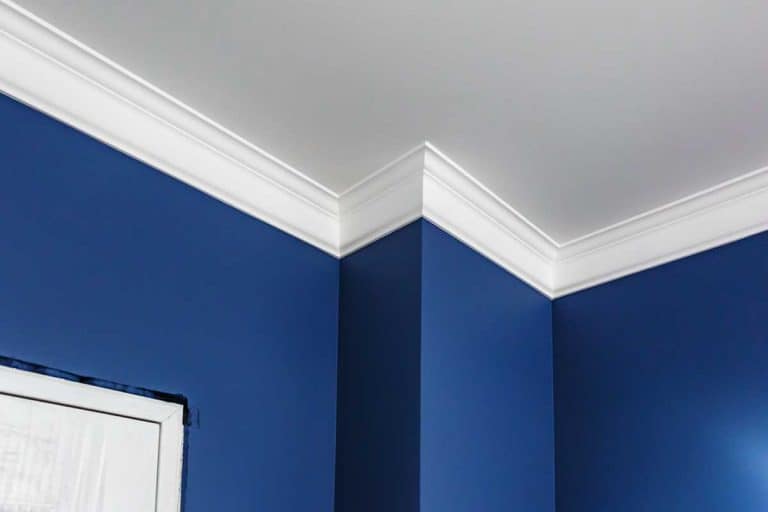 Detail of corner ceiling with intricate crown molding, Should You Paint Crown Molding Before Installation?