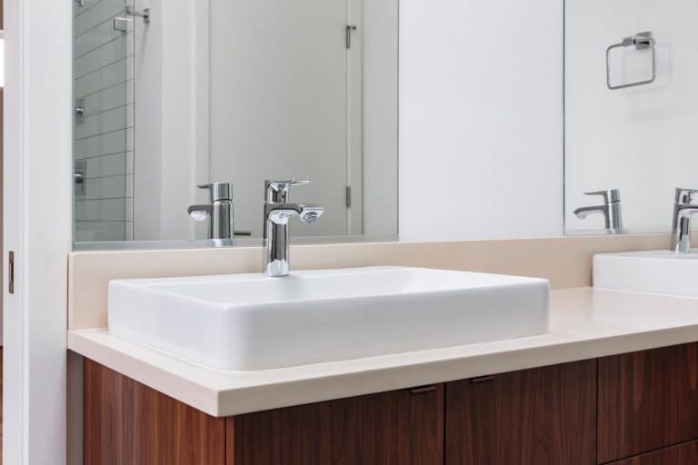 Modern bathroom with a white sink and wooden cabinets on the bottom, Will A Kitchen Faucet Fit A Bathroom Sink?