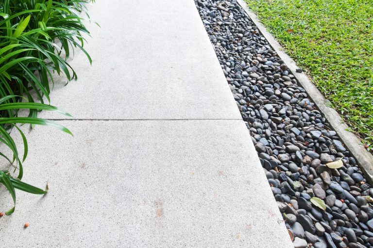 Pavement with river rocks on the side to boost landscaping on a garden, 10 Types Of Landscaping Rocks You Need To Know
