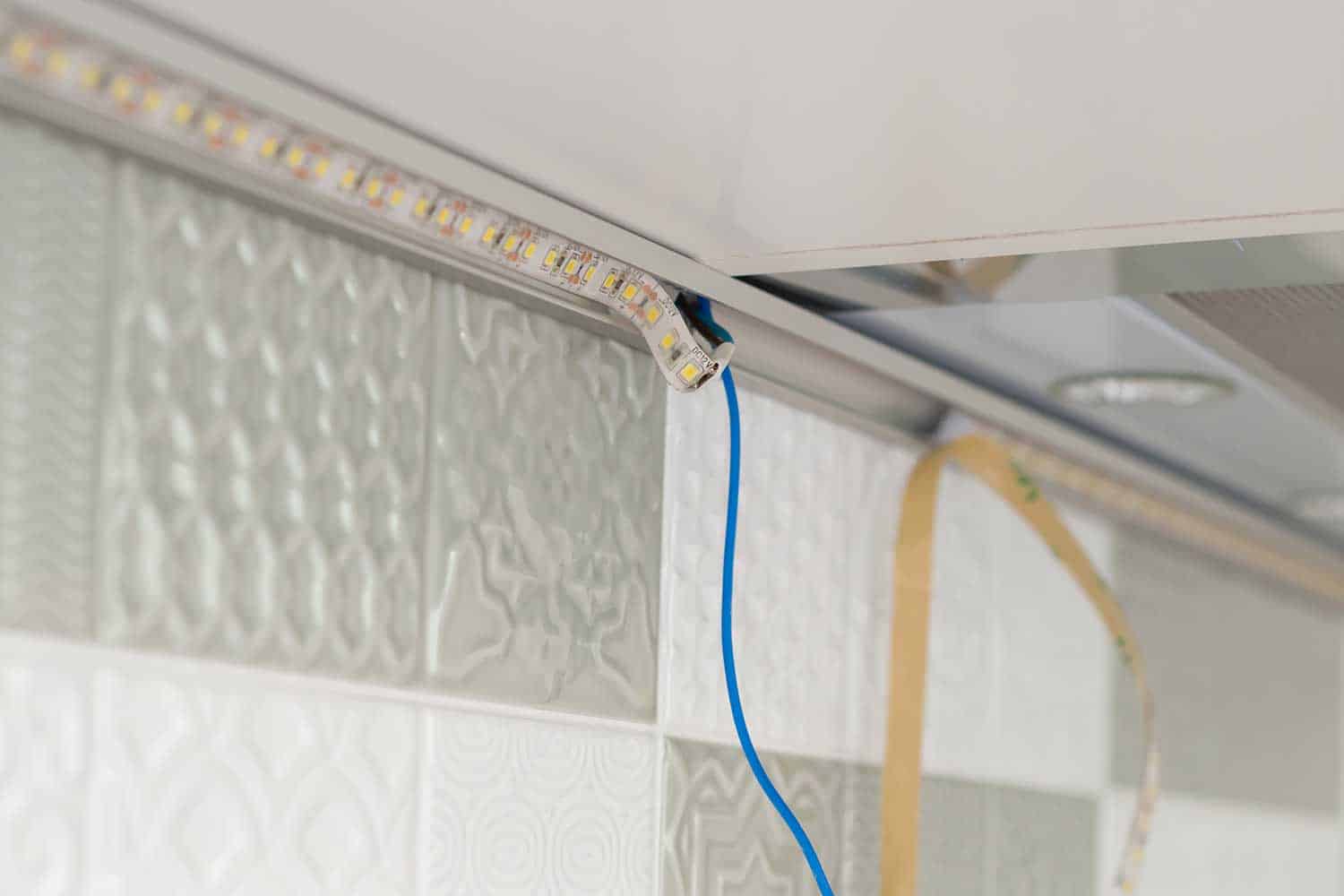 Close up installing LED strip on kitchen furniture