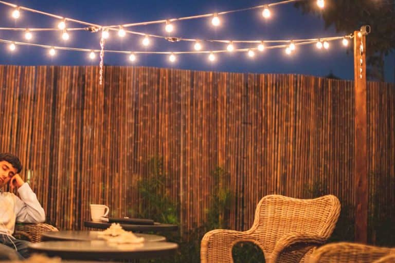 An outdoor patio setup in the gravel backyard garden with bamboo fence, How Long Does a Bamboo Fence Last? [and How to Make It Last Longer]