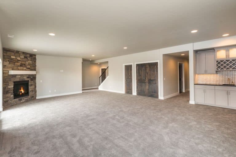 A gorgeous newly furnished basement with a carpeted flooring, off white painted walls, and a gray ceiling, How Much Does Basement Encapsulation Cost?