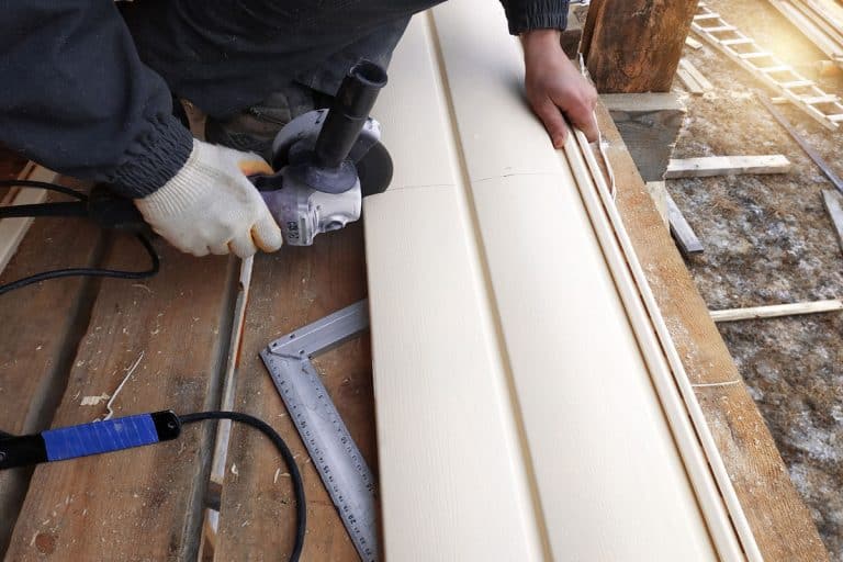 A worker cutting vinyl siding for a house, What Is The Best Tool To Cut Vinyl Siding?