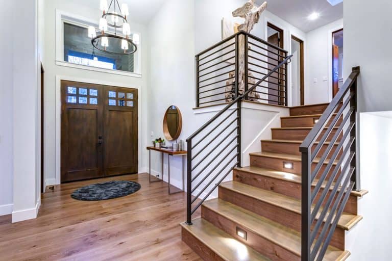 Interior of a modern contemporary living room with wooden flooring, wooden staircase with metal handrailing, and white painted walls, Are Stairs Required To Have A Handrail?
