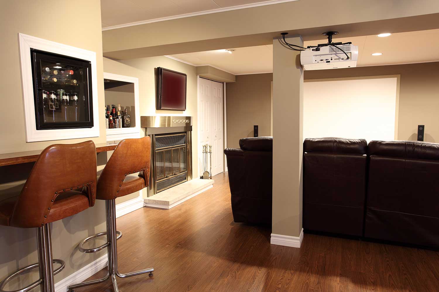 Modern living room located in the basement of a bungalow with a wooden floor, a bar, mini fridge and furniture