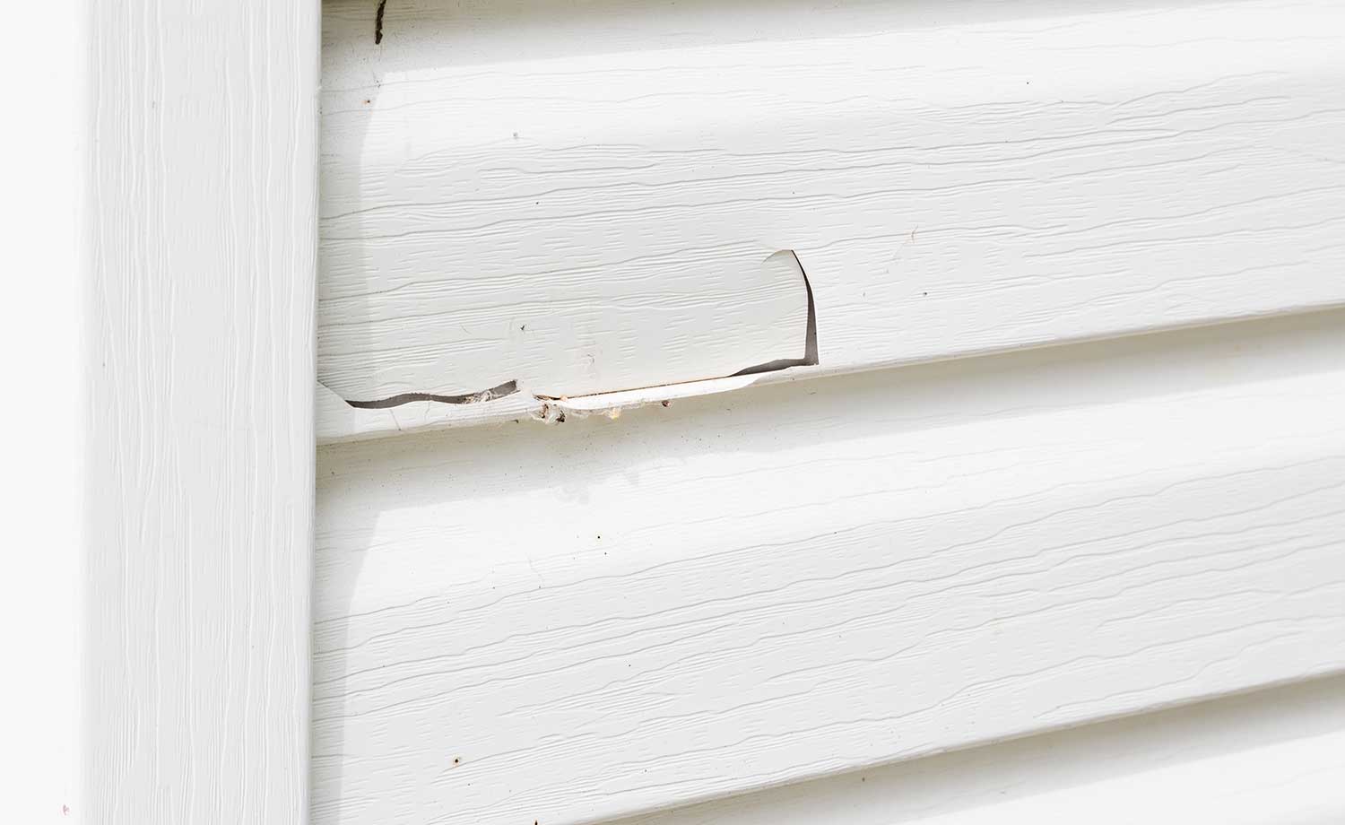 White plastic siding with a big crack in it