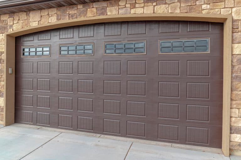 A huge brown colored garage door with decorative stones, Should You Replace Garage Door Springs In Pairs?