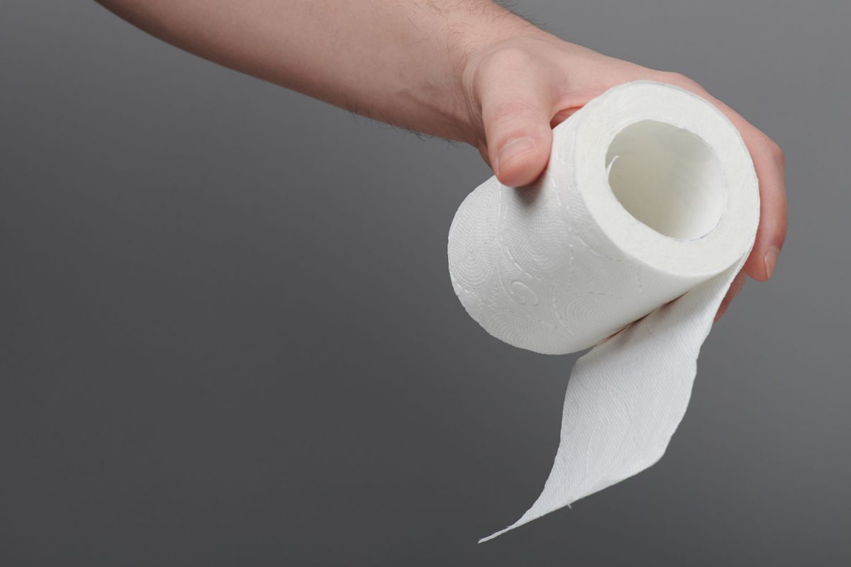 A woman holding a small roll of toilet paper