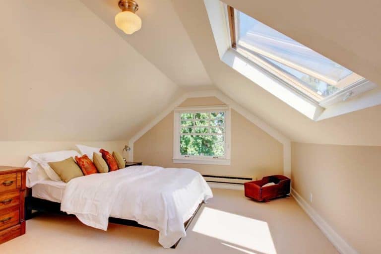 An attic bedroom with white bed and skylight, Can The Attic Be Converted To A Living Space? [And How To Go About That]
