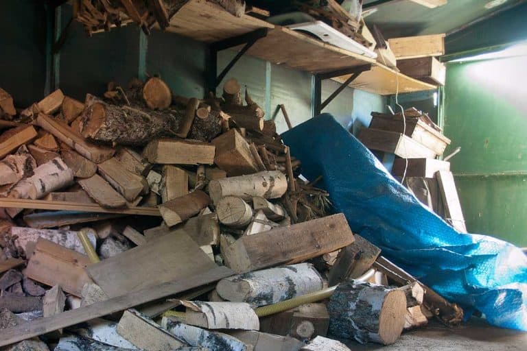 Pile of firewood and other household stuff in a garage, Should You Store Firewood In Your Garage?