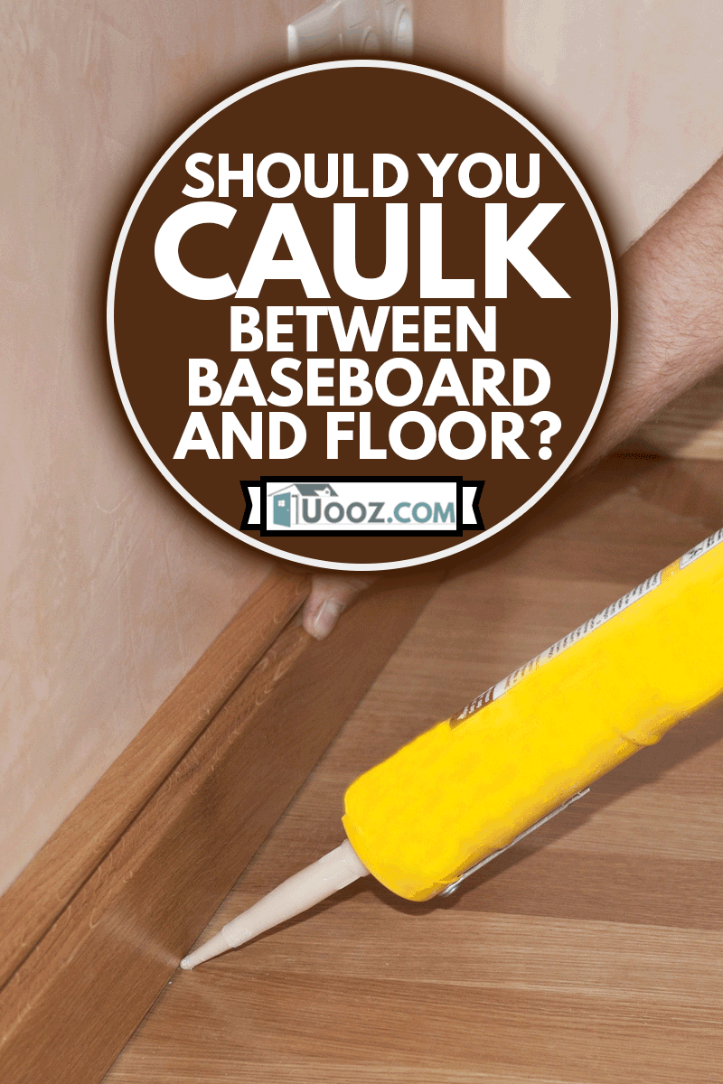Carpenter on work putting wood parquet skirting board with caulking gun, Should You Caulk Between Baseboard And Floor?