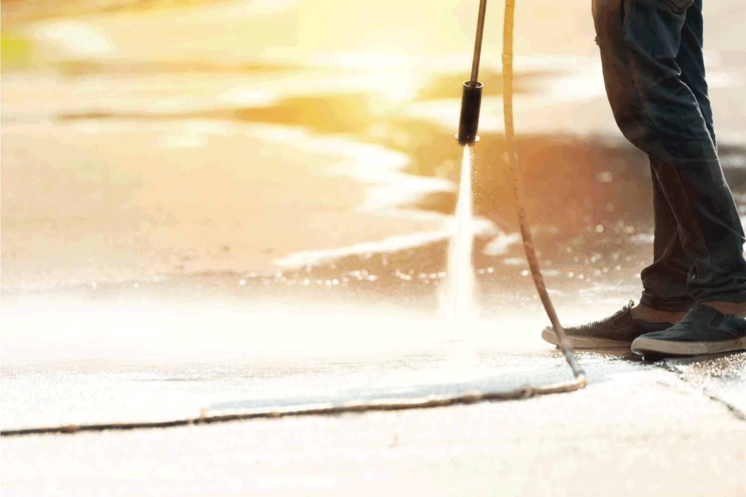 Worker cleaning driveway with gasoline high pressure washer splashing the dirt. Professional cleaning services.
