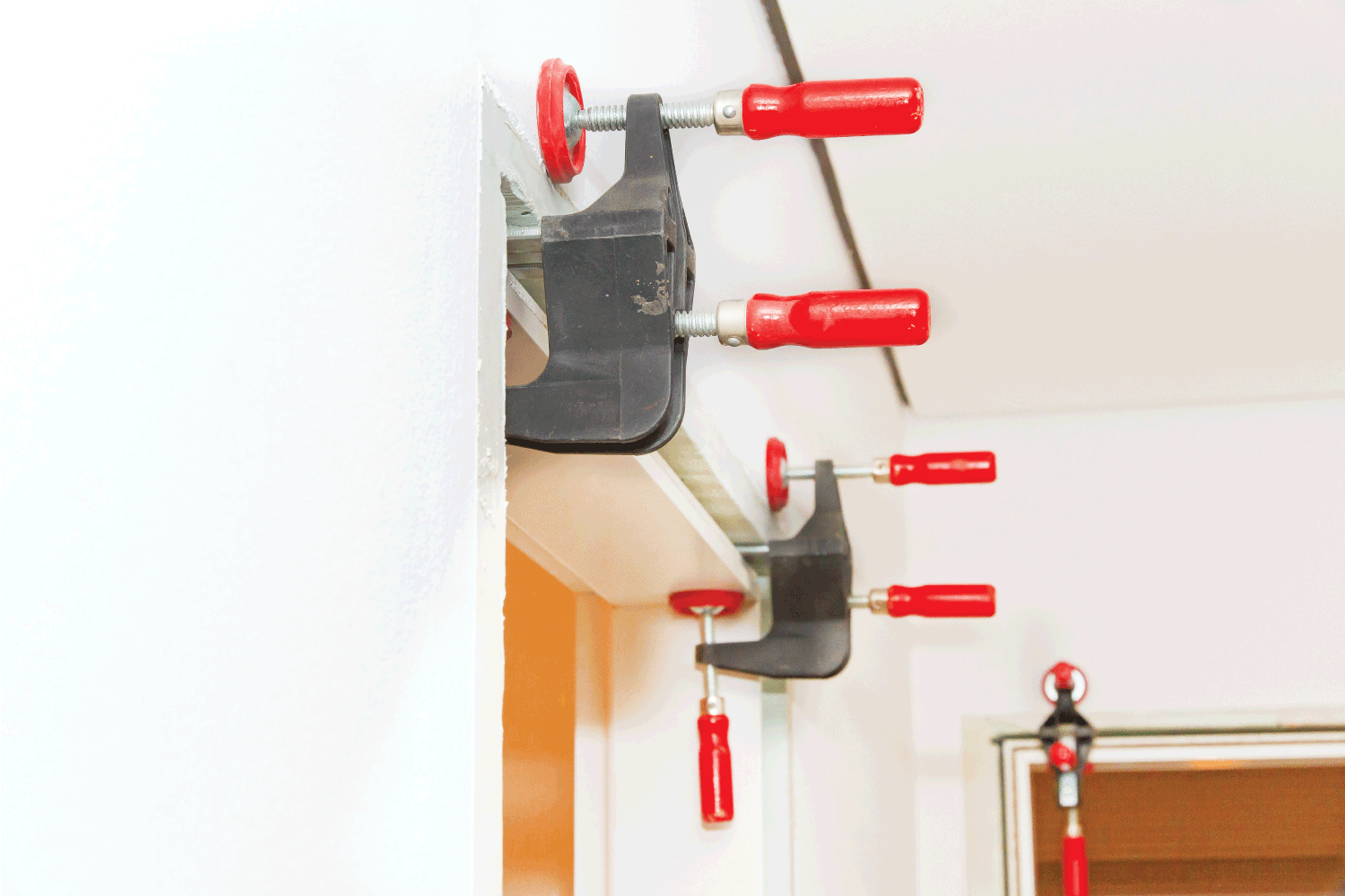 bar clamps holding up door jamb for installation to concrete wall