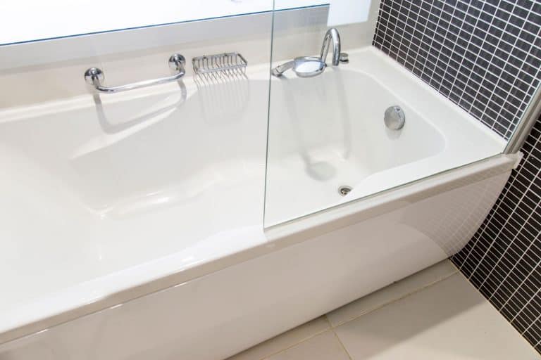 A huge ceramic bathtub inside a bathroom with small tiled backsplash, Can Bathtub Drain Pipes Freeze? [And How To Unfreeze Them]