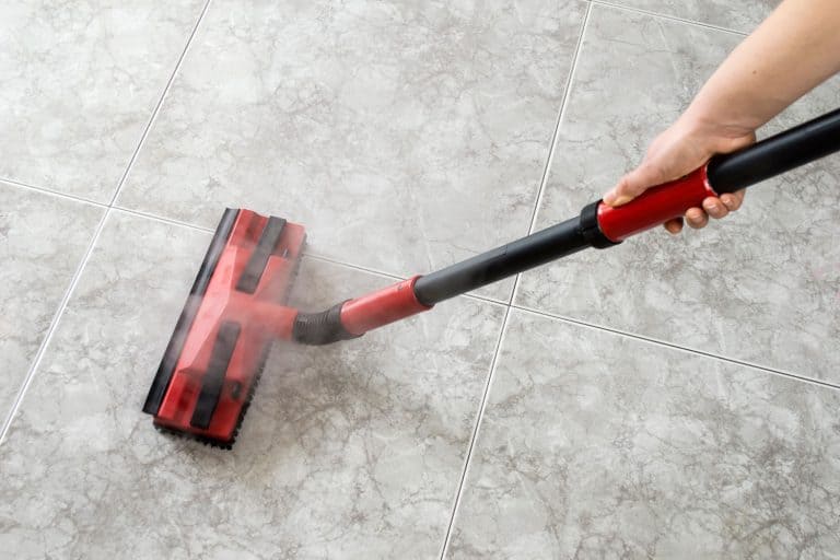 A man using a steam cleaner to remove the stain in the tile grout, Do Steam Cleaners Clean Floor Grout?