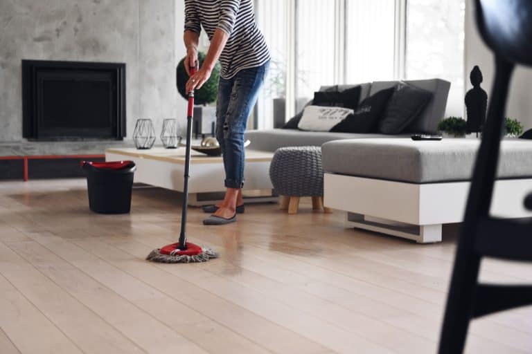 A woman mopping the floor of her living room, Should You Mop The Floor With Bleach?