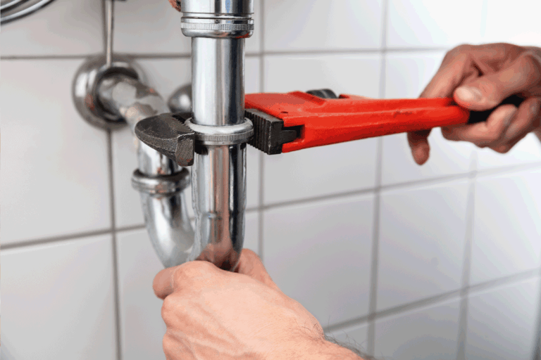 Close-up Of A Plumber's Hand Repairing Sink With Adjustable Wrench. What Size Drain Pipe For Bathroom Sink