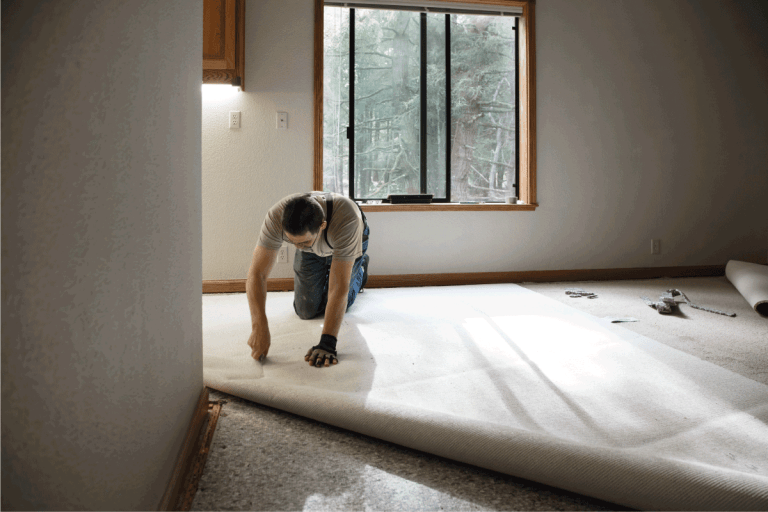 man cutting and installing new carpet at home