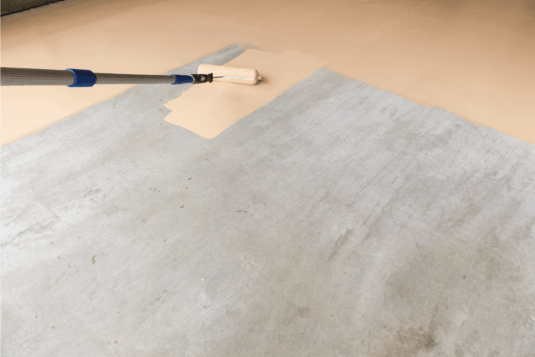 paint roller spreading paint on concrete garage floor. Should You Paint The Garage Floor