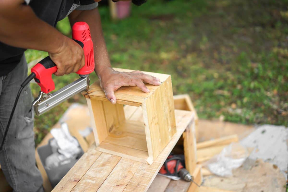 A man using a nail gun to make his wood work project