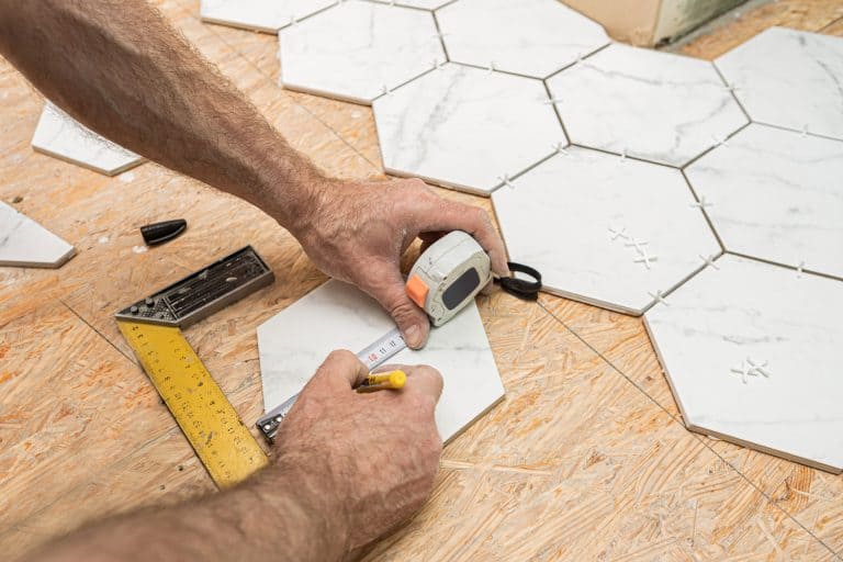 A tile setter placing hexagonal tiles inside a bathroom, How To Grout Hexagon Floor Tile [4 Steps To Follow!]