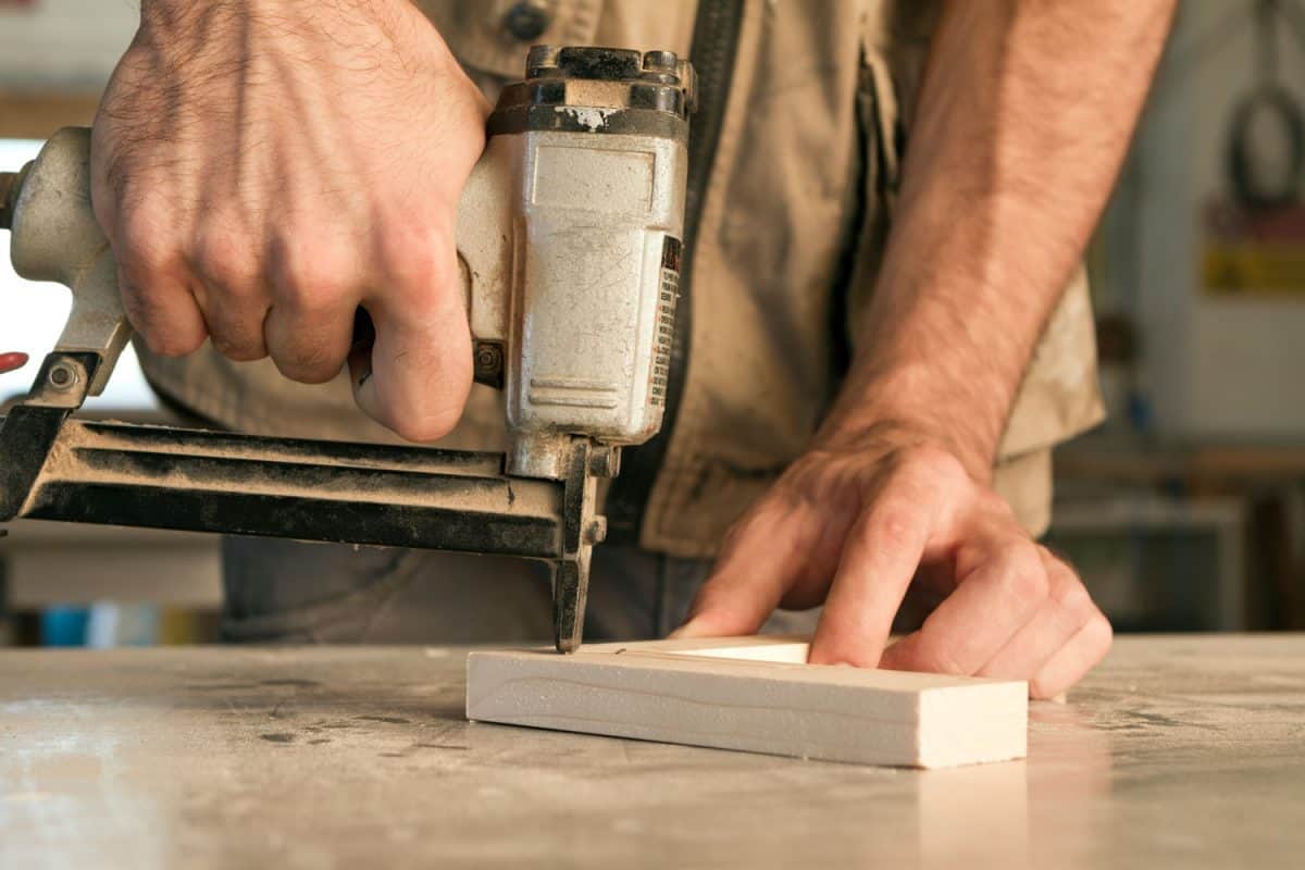 A worker using a nail gun on his workpiece