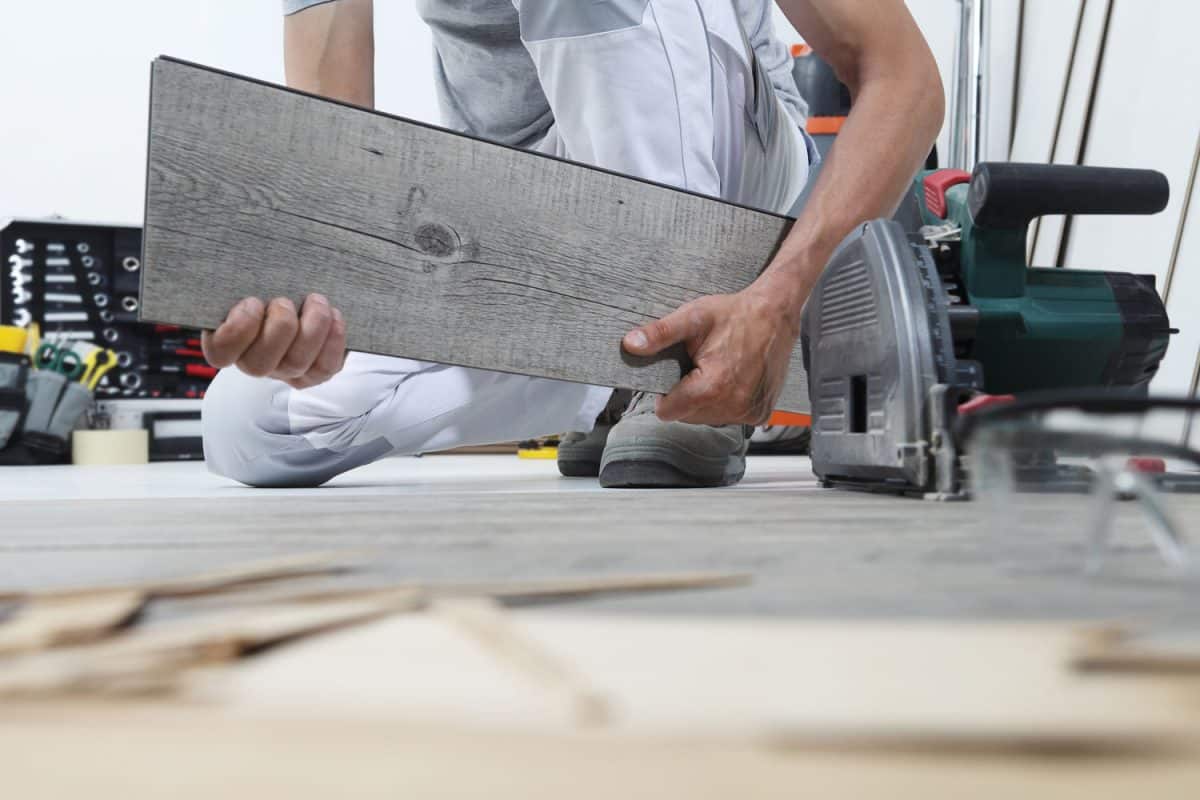 Worker hands installing timber laminate vinyl floor. Wooden floors house renovation, How To Grout Vinyl Floor Tiles - 4 Steps To Follow