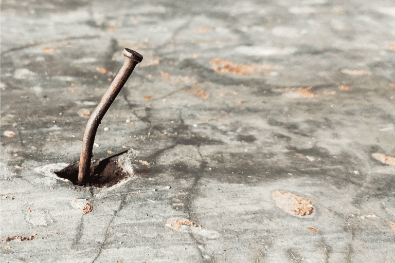 An old rusty bending nail in the concrete. How To Remove Nails From Concrete Floor