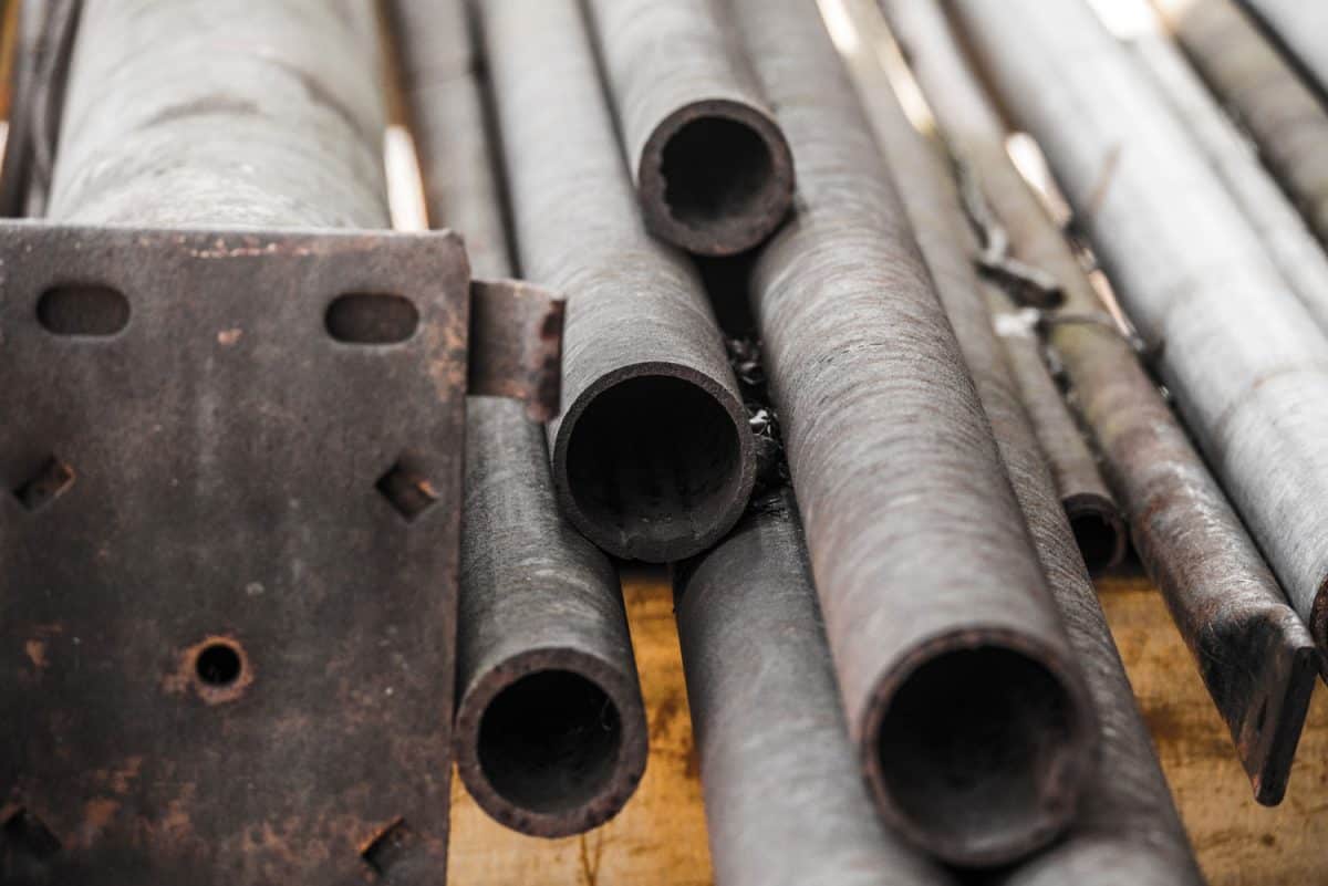Close up photograph of the ends of a pile of random weathered and rusted pieces of steel, iron and galvanized round pipe or tube steel sections or extrusions making a great industrial type background