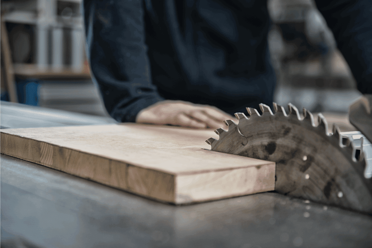 A man operating a table saw in a woodworking shop. How To Cut Hardwood Flooring Around Door Jambs