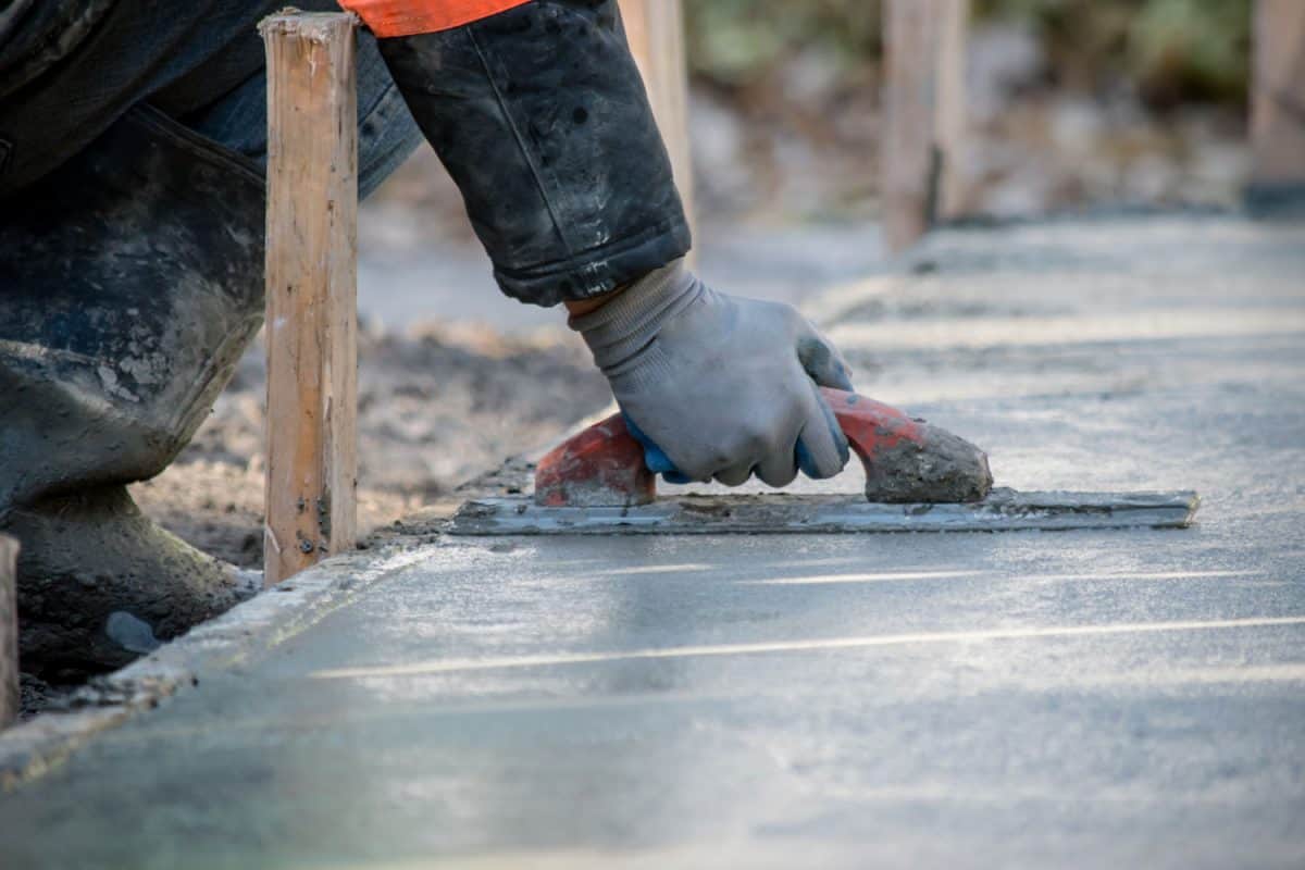 A worker using a trowel in spreading the concrete pour for the foundation