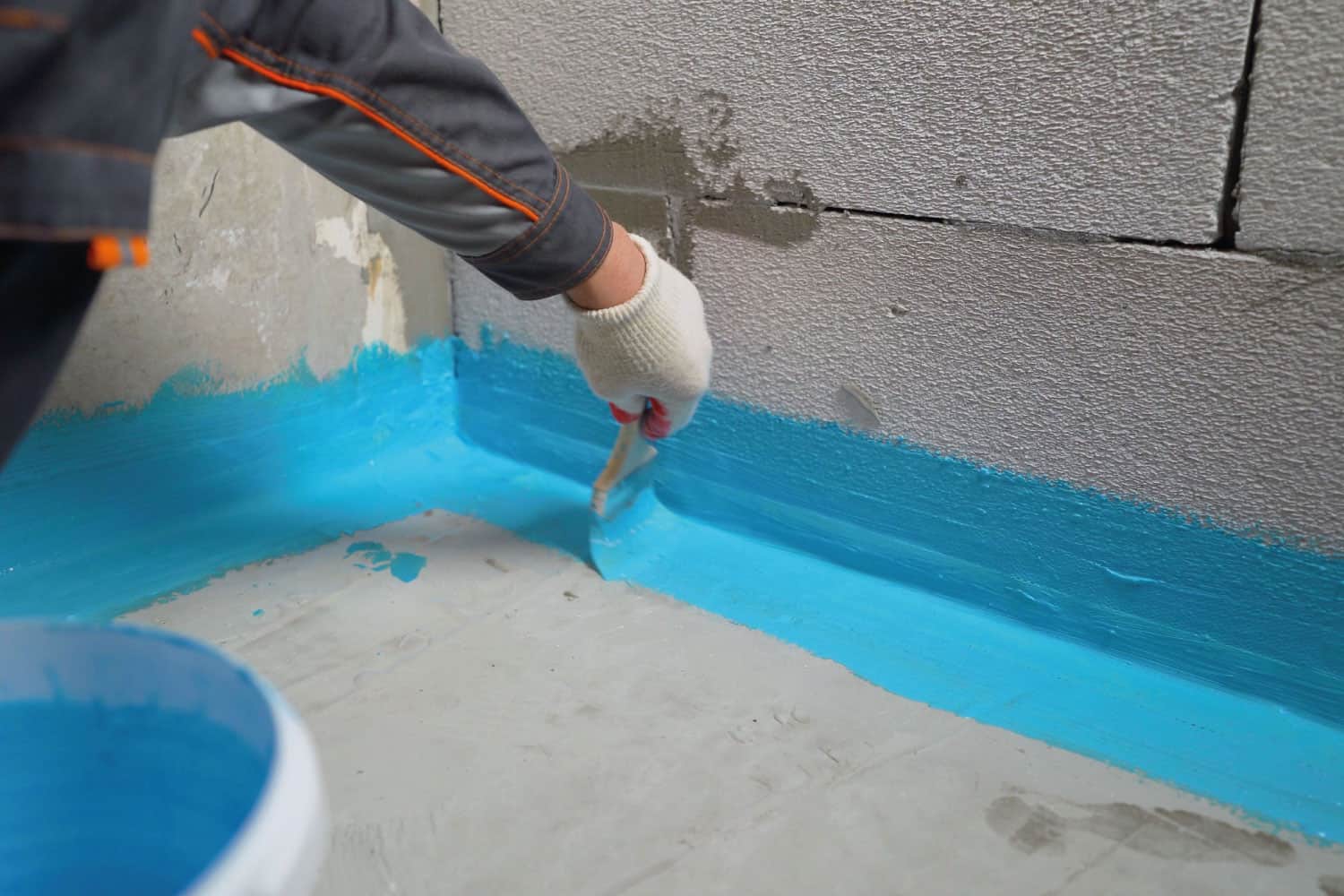 Cover the concrete wall with a cement-polymer waterproofing membrane. Waterproofing with a blue shade brush.