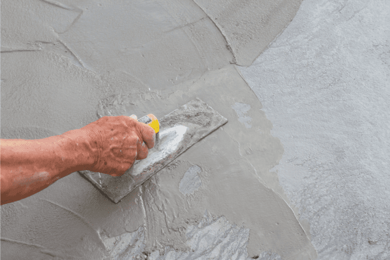 Hand-using-trowel-on-fresh-mortar-in-construction-site.-What-Type-Of-Mortar-To-Use-Under-Shower-Base