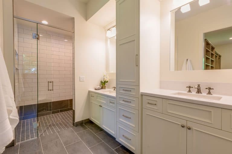 Interior of a classic designed bathroom with white cabinets and drawers with brown tiles on the flooring and shower base, How To Install A Shower Base On Concrete Floor