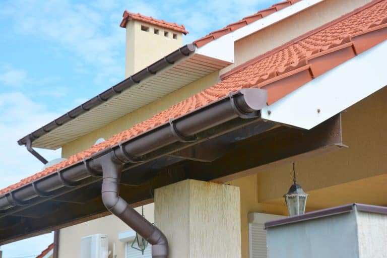 A reinforced gutter painted in brown of a modern house with metal roofing, How To Keep Water Away From House Foundations