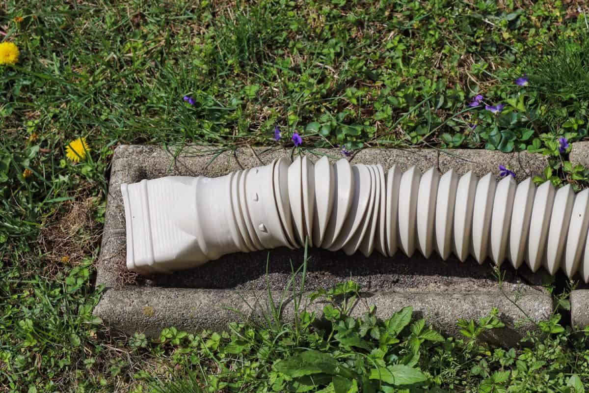 A vertical gutter downspout hose leading to the public drainage