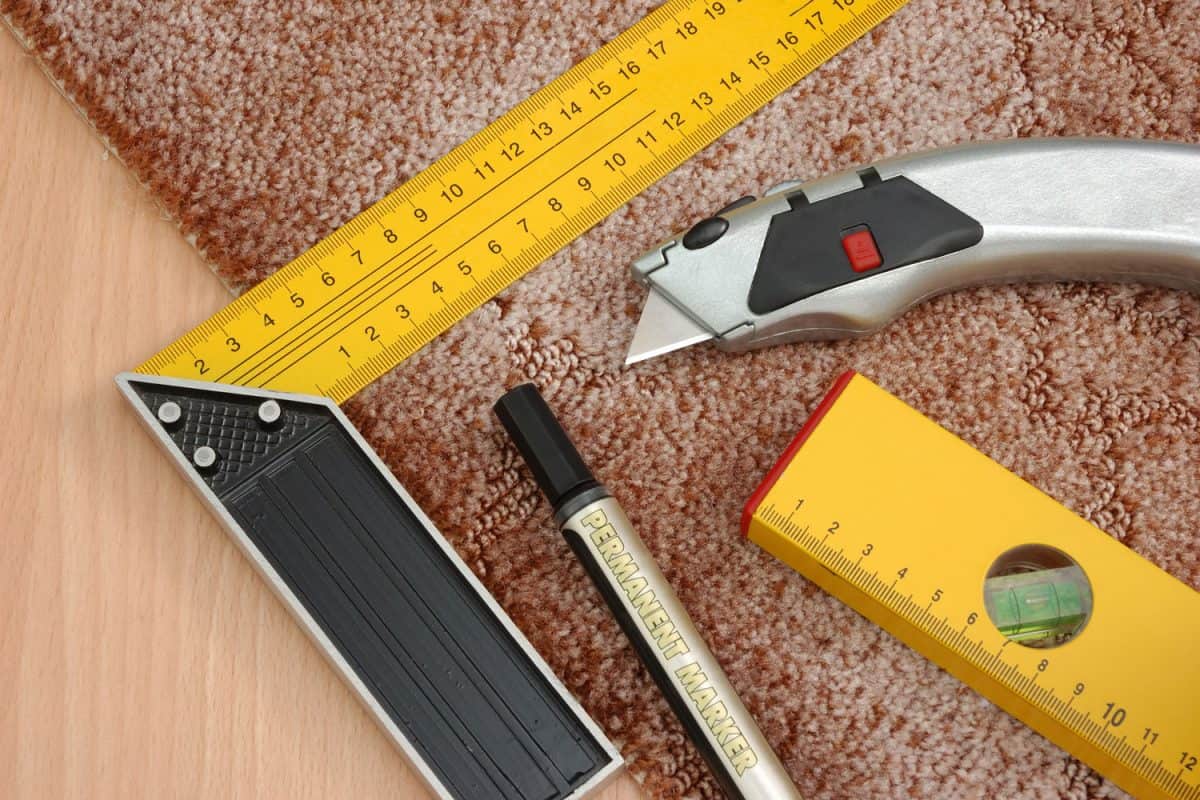 Measuring tools, level bar, markers and cutter placed on the carpet