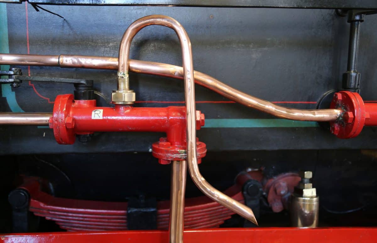 A leaf spring and copper piping on an old steam locomotive.