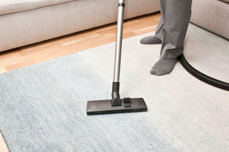 A man wearing slacks and gray sock while cleaning the carpet, Can You Bleach Carpet To Make It White? [And How To]
