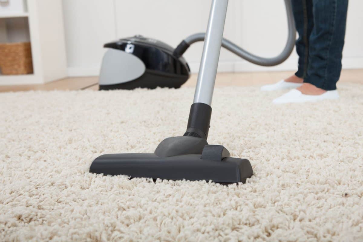 A woman cleaning the carpet using vacuum