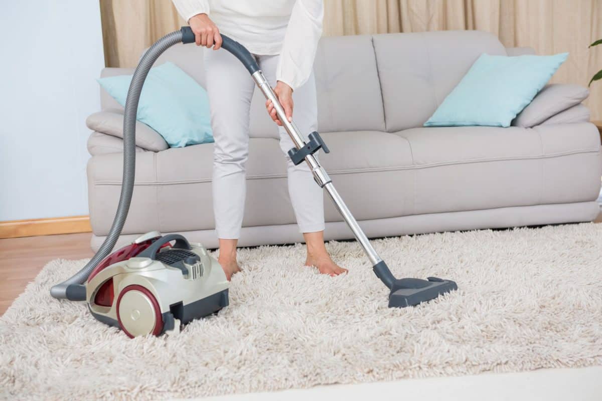 A woman cleaning the carpet using a vacuum