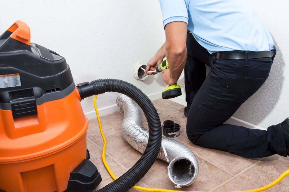 A worker cleaning the dryer vent using a vacuum