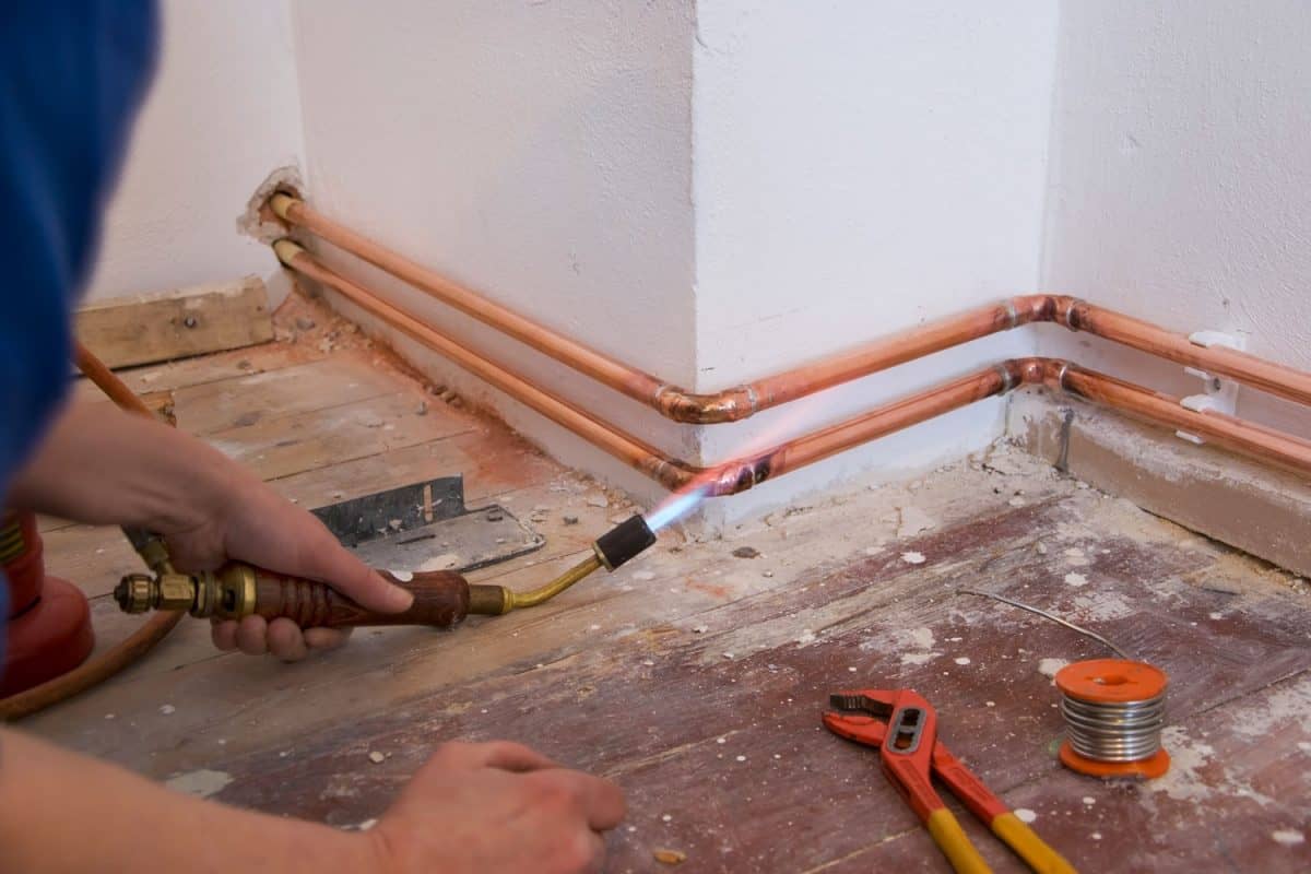 A worker installing a copper pipe for the water line in the kitchen
