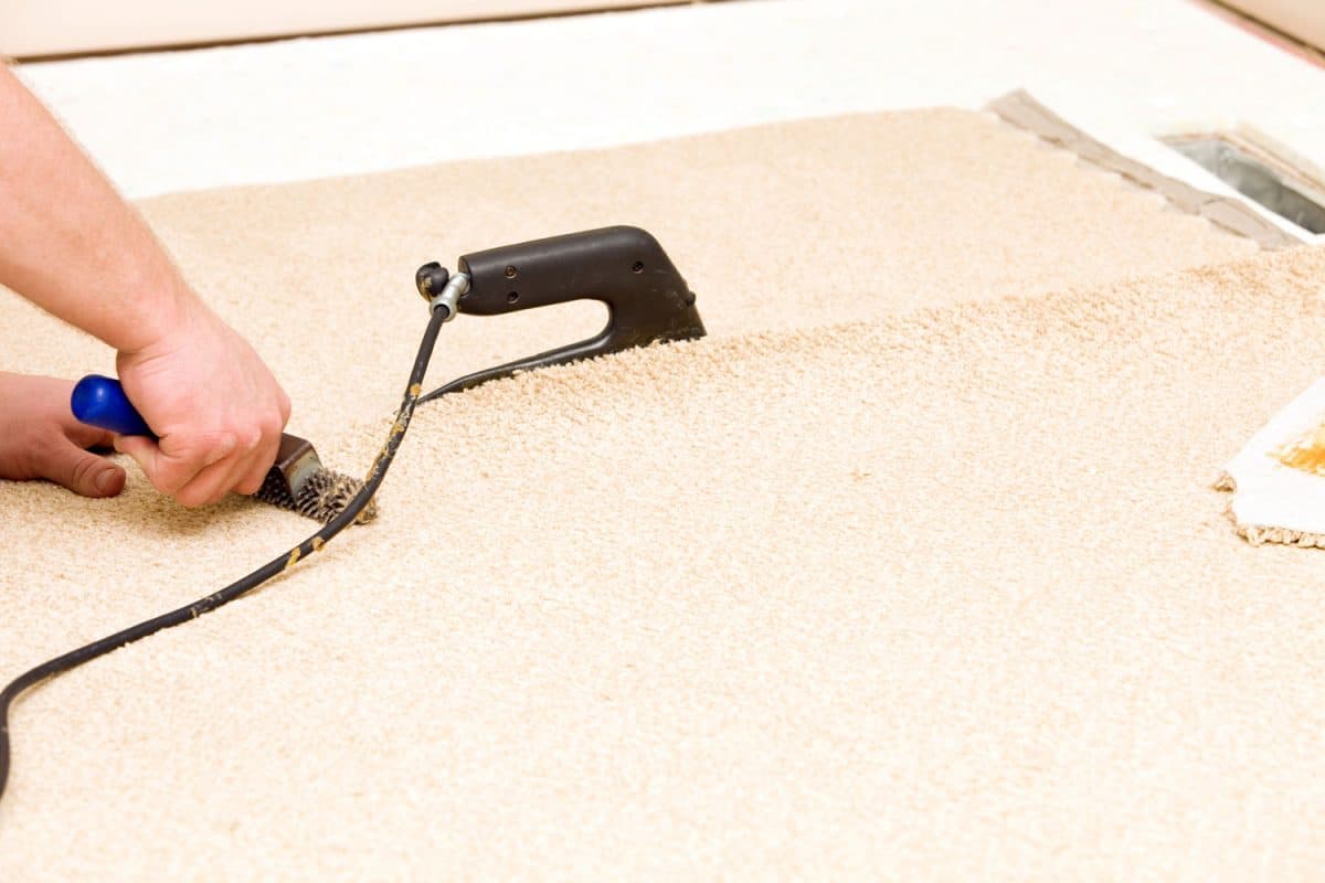 A worker using a seaming iron to join two pieces of carpet