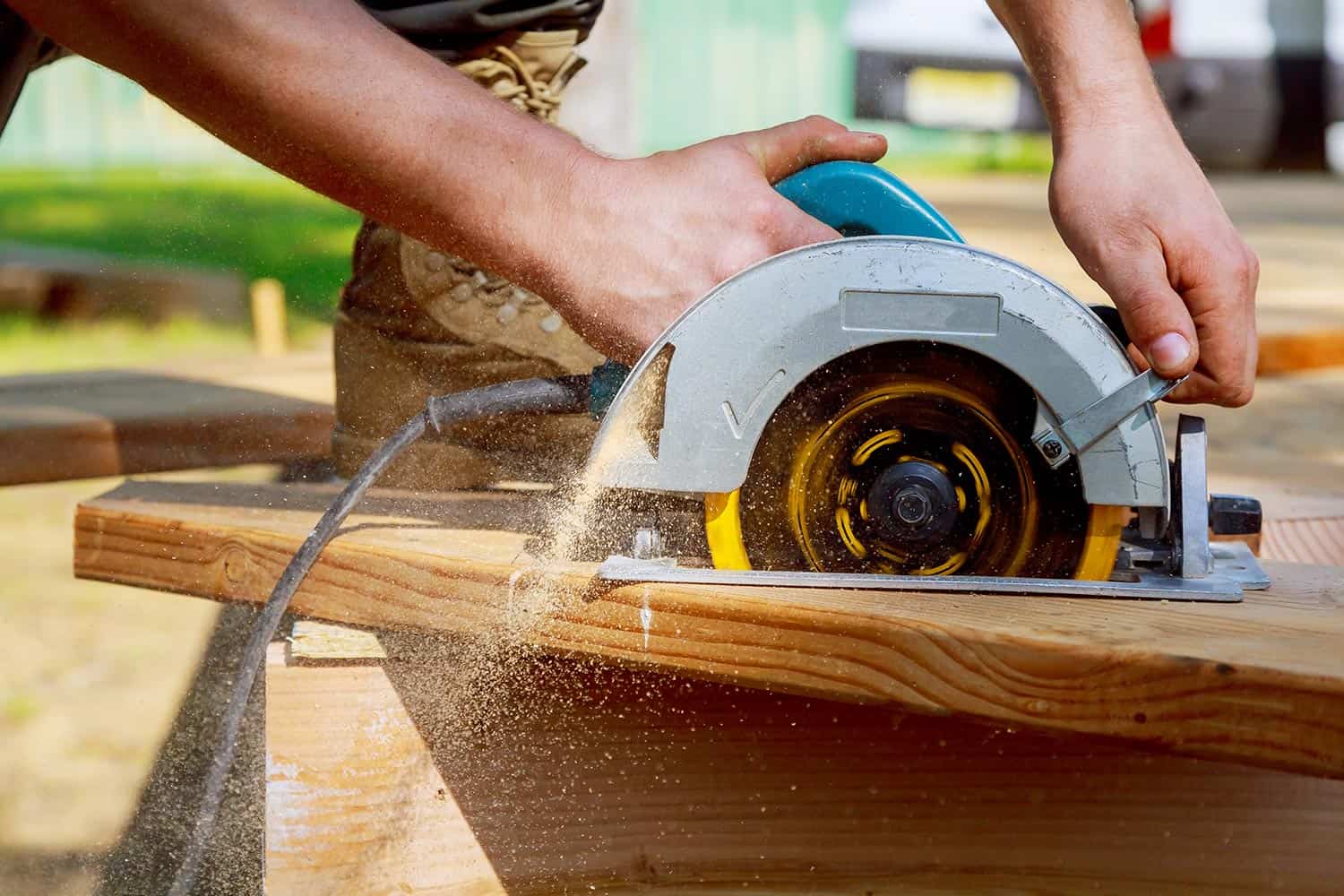 Builder saws a board with a circular saw cutting a wooden plank